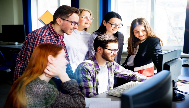 students collaborating around computer in office